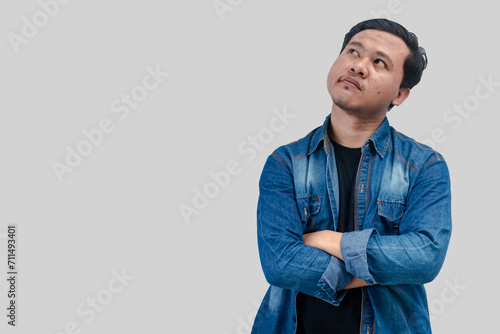Young Asian Man thinking about question, pensive expression. while hand arms folded. On isolated background