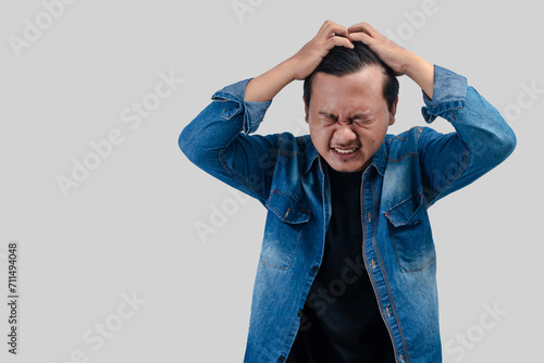 Young Asian Man with depressed expression with palms facing head. On isolated background