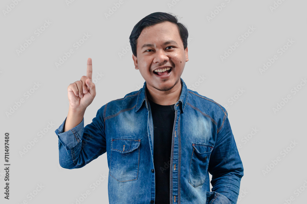 Young asian man pointing hand up to empty space on isolated background Young asian man pointing hand up to empty space on isolated background