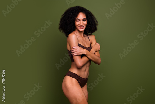 Studio no retouch photo of cheerful pretty lady dressed lingerie hugging accepting herself isolated green color background