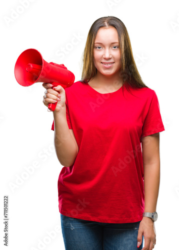 Young caucasian woman yelling through megaphone over isolated background with a happy face standing and smiling with a confident smile showing teeth