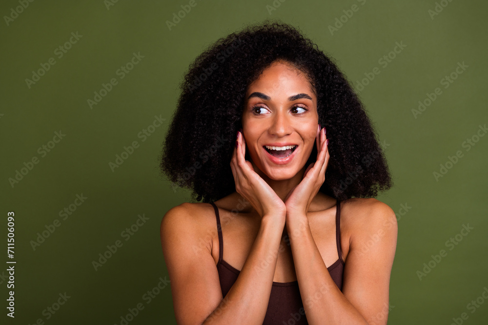 Studio no retouch photo of smiling excited lady dressed lingerie hands arms cheeks looking empty space isolated green color background Studio no retouch photo of smiling excited lady dressed lingerie hands arms cheeks looking empty space isolated green color background
