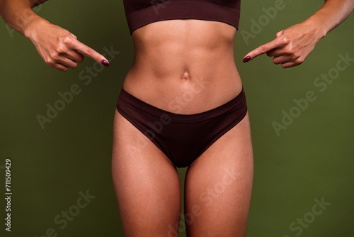 Cropped no retouch photo of female belly with strong abdominal abs sporty figure isolated on khaki color background © deagreez