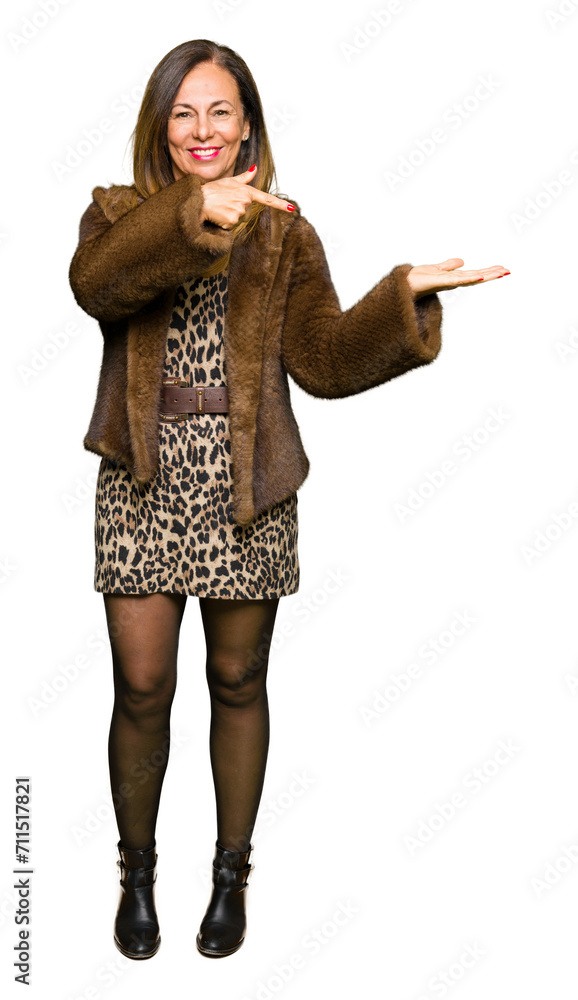 Beautiful middle age elegant woman wearing mink coat amazed and smiling to the camera while presenting with hand and pointing with finger. Beautiful middle age elegant woman wearing mink coat amazed and smiling to the camera while presenting with hand and pointing with finger.