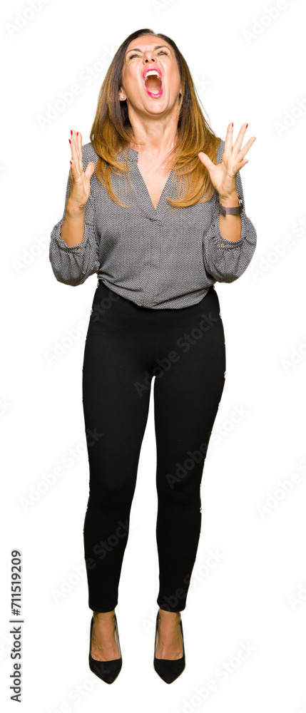 Beautiful middle age business woman crazy and mad shouting and yelling with aggressive expression and arms raised. Frustration concept.