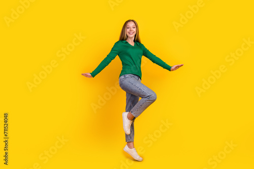 Full body length photo of charming girl teenager in green jumper denim jeans white sneakers freedom isolated on yellow color background