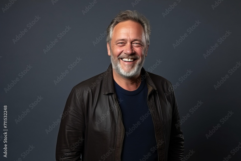 Portrait of a happy senior man in leather jacket smiling against grey background