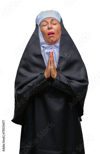 Middle age senior christian catholic nun woman over isolated background begging and praying with hands together with hope expression on face very emotional and worried. Asking for forgiveness