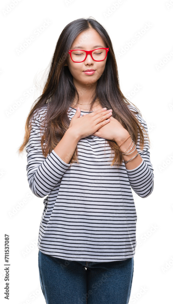 Young asian woman wearing glasses over isolated background smiling with hands on chest with closed eyes and grateful gesture on face. Health concept. Young asian woman wearing glasses over isolated background smiling with hands on chest with closed eyes and grateful gesture on face. Health concept.