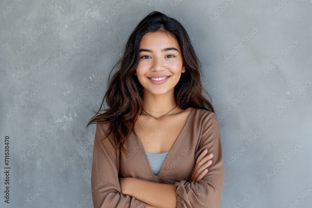 Smiling Latin woman with crossed arms on grey wall. Smiling Latin woman with crossed arms on grey wall.