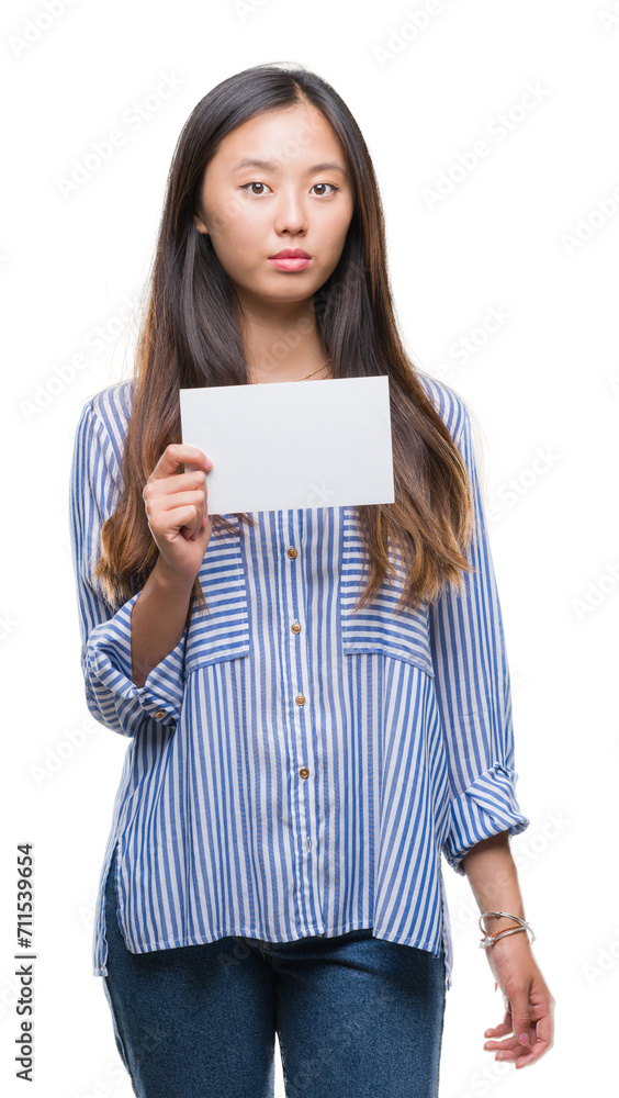 Young asian woman holding blank card over isolated background with a confident expression on smart face thinking serious Young asian woman holding blank card over isolated background with a confident expression on smart face thinking serious