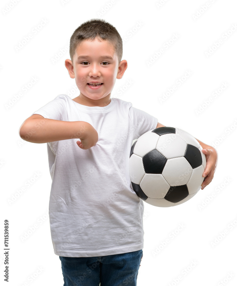Dark haired little child playing with soccer ball with surprise face pointing finger to himself