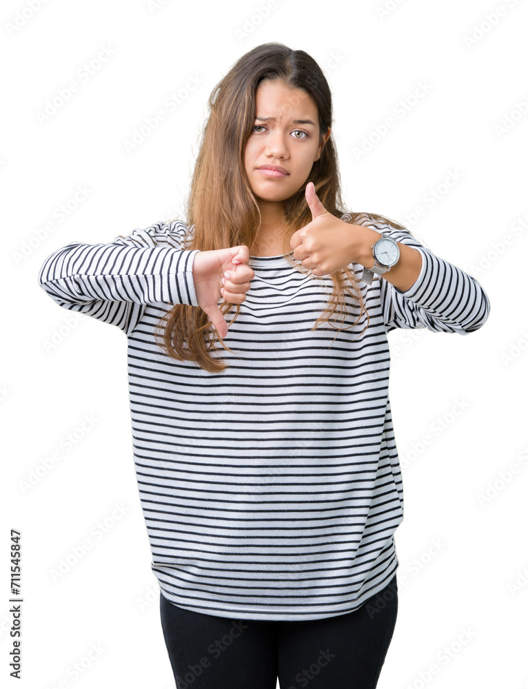 Young beautiful brunette woman wearing stripes sweater over isolated background Doing thumbs up and down, disagreement and agreement expression. Crazy conflict Young beautiful brunette woman wearing stripes sweater over isolated background Doing thumbs up and down, disagreement and agreement expression. Crazy conflict
