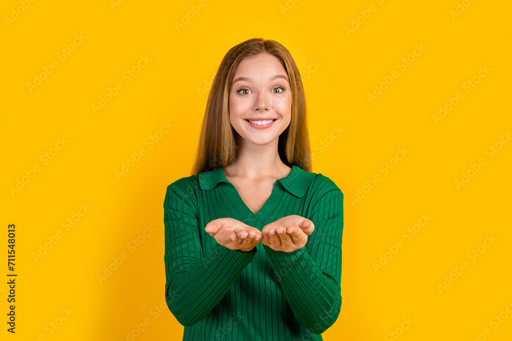 Photo of friendly pretty girl beaming smile arms palms hold demonstrate empty space offer isolated on yellow color background