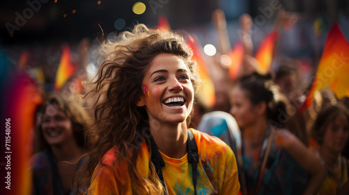 A girl in orange smiles in the crowd at the Holi festival.