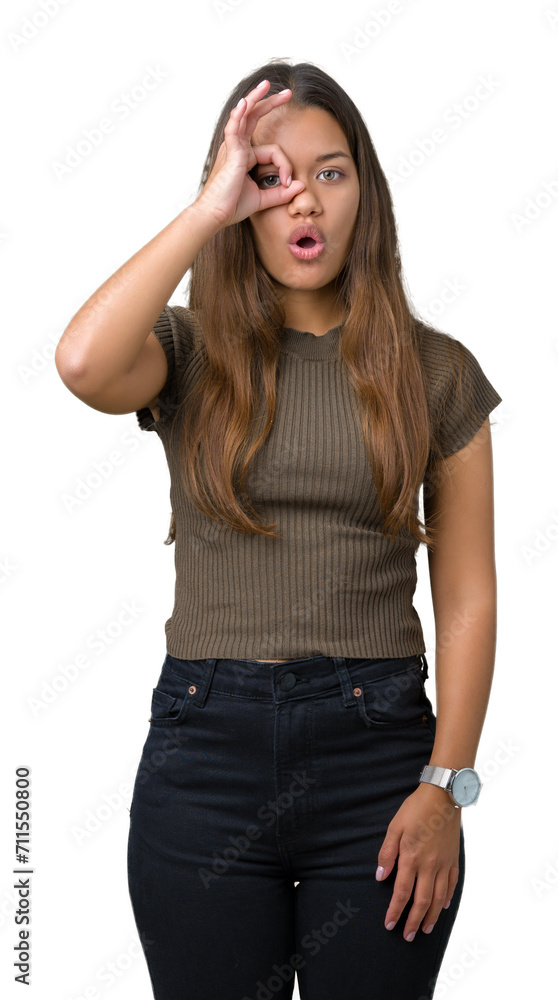 Young beautiful brunette woman over isolated background doing ok gesture shocked with surprised face, eye looking through fingers. Unbelieving expression. Young beautiful brunette woman over isolated background doing ok gesture shocked with surprised face, eye looking through fingers. Unbelieving expression.