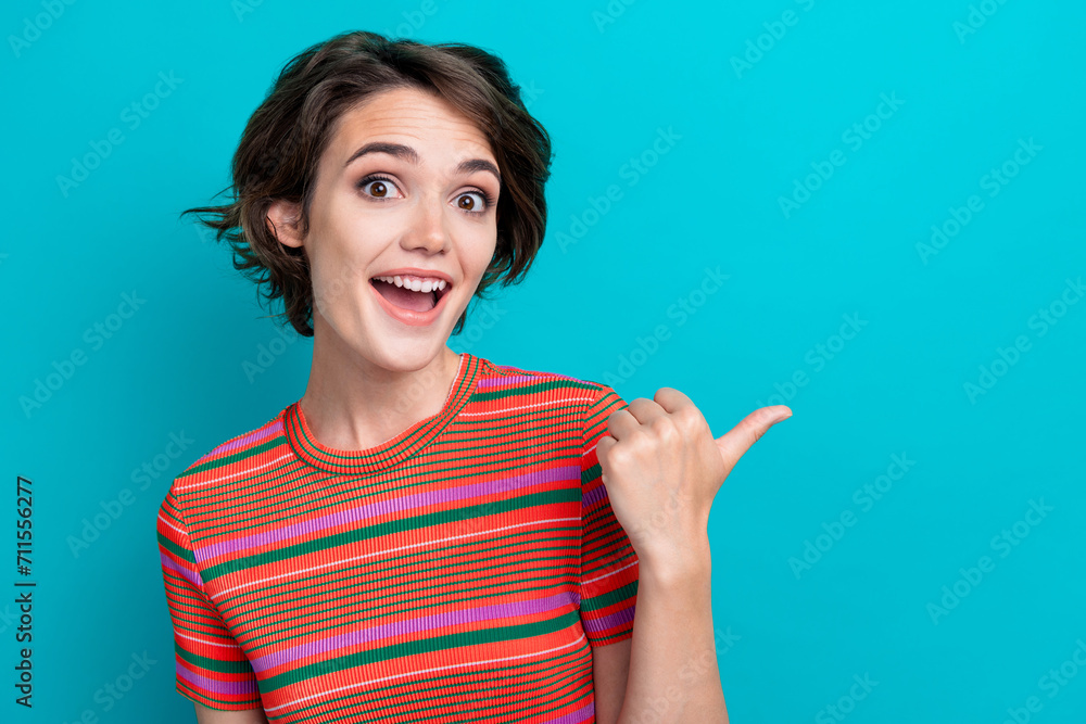 Photo of impressed ecstatic woman dressed striped t-shirt directing at discount empty space isolated on turquoise color background Photo of impressed ecstatic woman dressed striped t-shirt directing at discount empty space isolated on turquoise color background