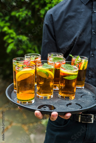 Server holding Pimm's cocktails at an outdoor event.