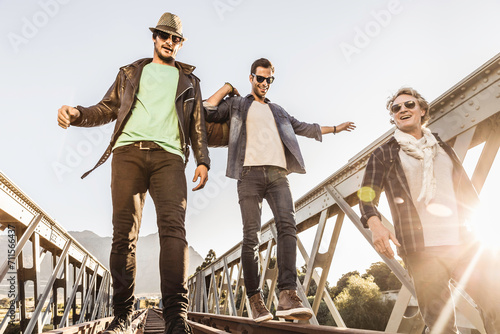 Group of friends walking across and hanging out on train bridge in the evening sun, Boho Style. Paarl, South Africa photo
