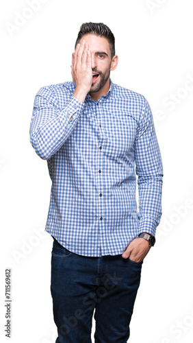 Young handsome man over isolated background covering one eye with hand with confident smile on face and surprise emotion.