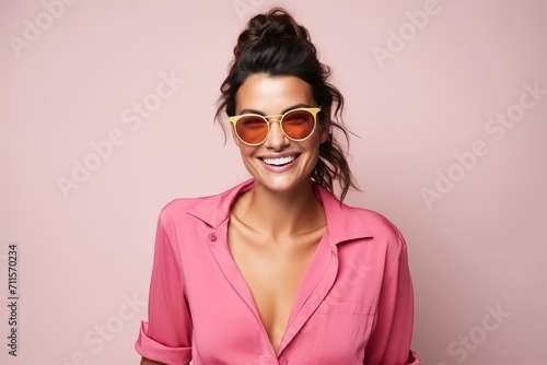 Portrait of a beautiful smiling woman in sunglasses over pink background.