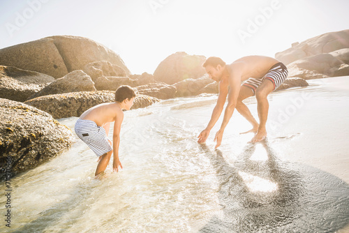 Mixed race father and son having fun playing on the beach. Cape Town, South Africa photo