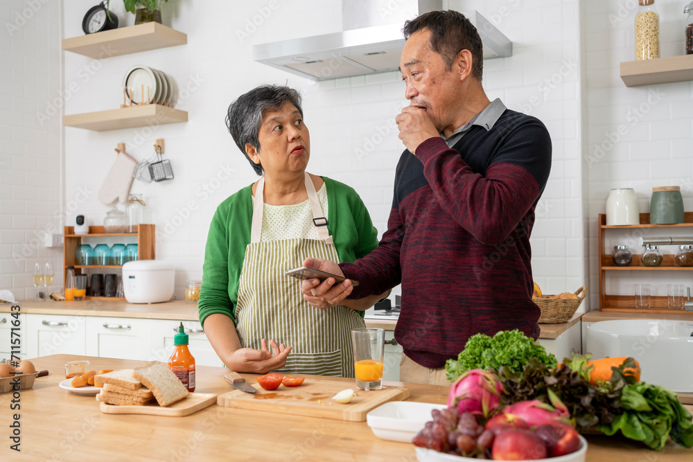 Attractive mature couple eating sandwich and use smartphone  in kitchen