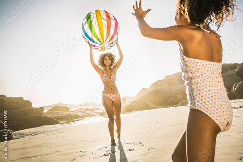 Mixed race mother and daughter having fun and playing on the beach. photo