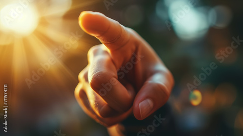 Close-up of a Caucasian hand pointing with a finger at the sun outdoors, sunny day