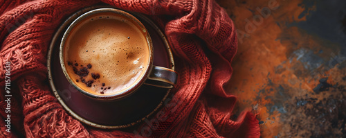 Close up photo cup of cappuccino coffee with foam on knitted burgundy fabric. Hot warming fresh drink in a cozy atmosphere. Top view banner with empty space. Concept for cafe, bar, barista, morning. photo