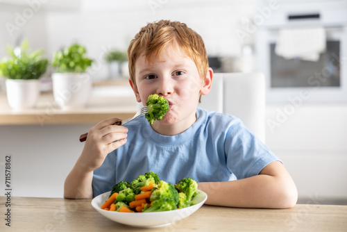A little boy is having lunch and eating broccoli