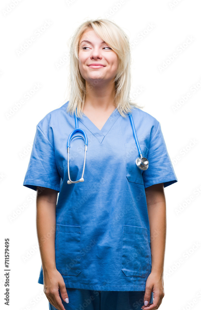 Young beautiful blonde doctor woman wearing medical uniform over isolated background smiling looking side and staring away thinking. Young beautiful blonde doctor woman wearing medical uniform over isolated background smiling looking side and staring away thinking.
