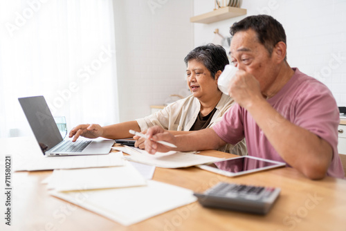 Happy Asian senior couple use digital technology device to working at home