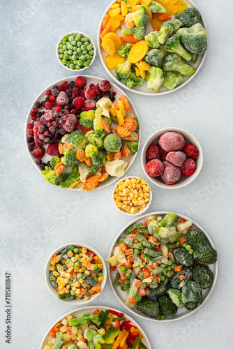 Preparing fresh vegetables in summer for winter, various frozen vegetables and berries in plates on a gray background, top view