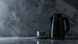 A sleek black electric kettle beside a matching cup on a grey background