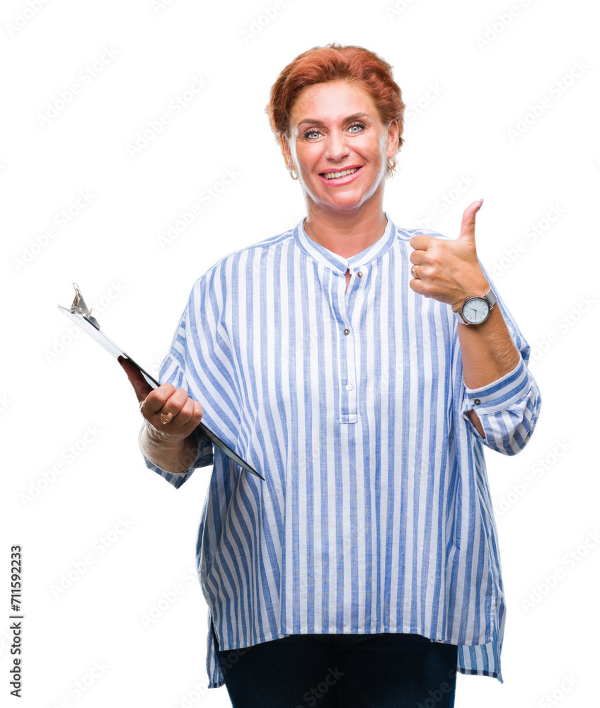 Senior caucasian business woman holding clipboard over isolated background happy with big smile doing ok sign, thumb up with fingers, excellent sign Senior caucasian business woman holding clipboard over isolated background happy with big smile doing ok sign, thumb up with fingers, excellent sign