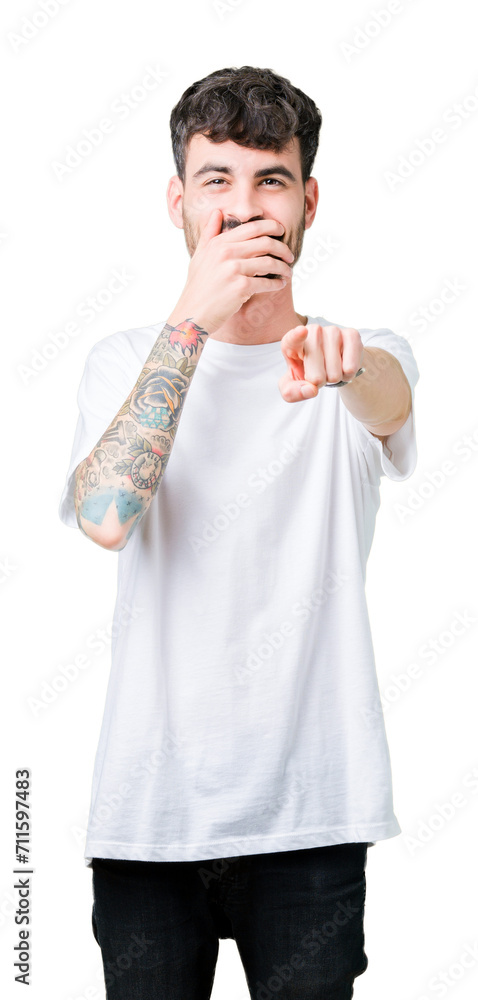 Young handsome man wearing white t-shirt over isolated background Laughing of you, pointing to the camera with finger hand over mouth, shame expression Young handsome man wearing white t-shirt over isolated background Laughing of you, pointing to the camera with finger hand over mouth, shame expression