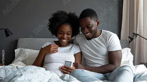 Parenthood, good news, baby expecting concept. Joyful dark skinned wife leans shoulder of her husband, look positively at pregnancy test, going to have child. Family couple on bed in modern apartment