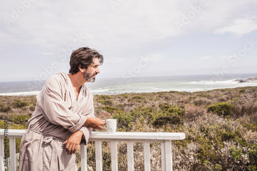 Man enjoying morning coffee in a bath robe at a beach house