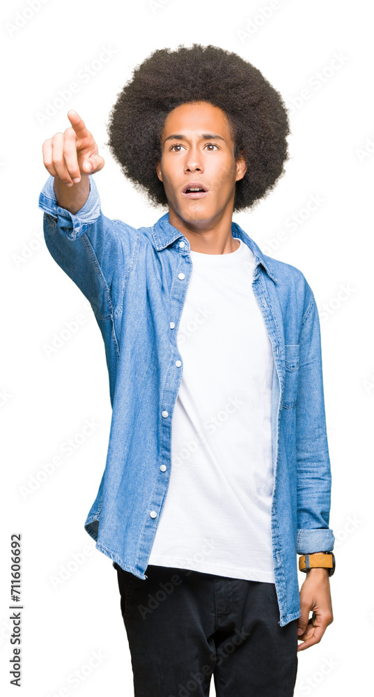 Young african american man with afro hair Pointing with finger surprised ahead, open mouth amazed expression, something in front