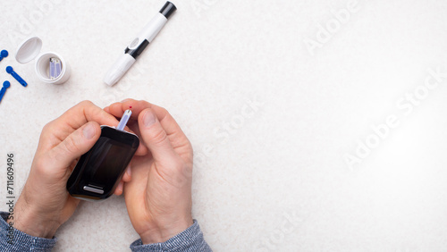 Foto Caucasian middle aged man hands to make home testing with glucose meter over table with strips and lancets with copy-space