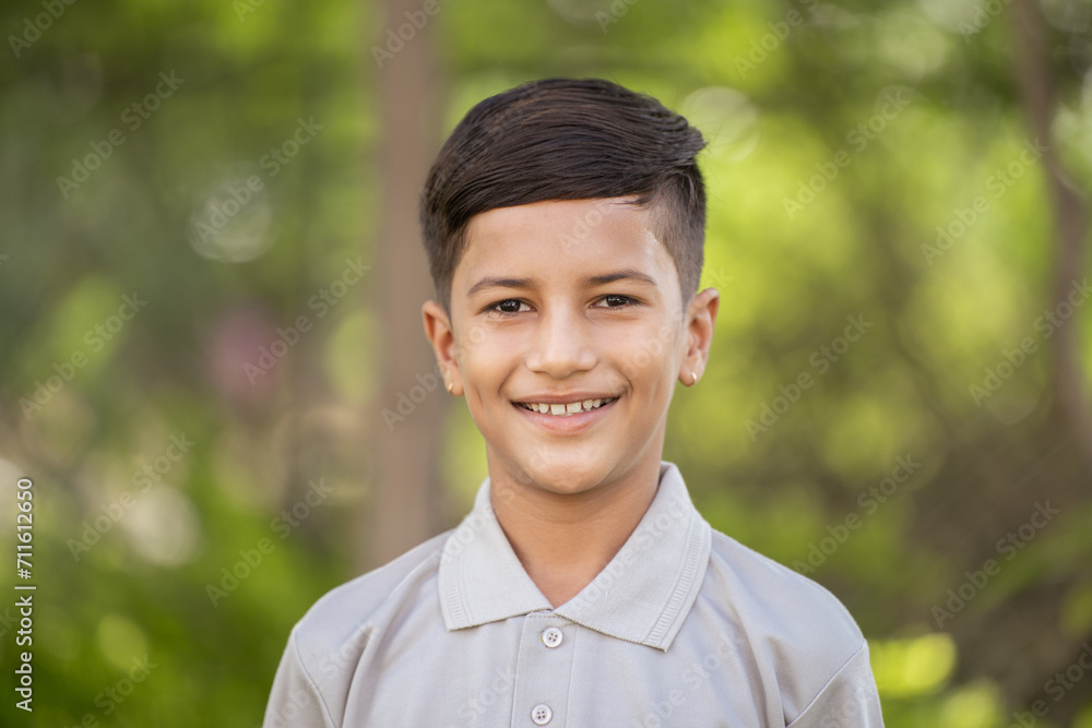 Happy smiling indian boy kid looking at camera at park - concept of Playful Expression, Outdoor Happiness and Joyful Child Happy smiling indian boy kid looking at camera at park - concept of Playful Expression, Outdoor Happiness and Joyful Child