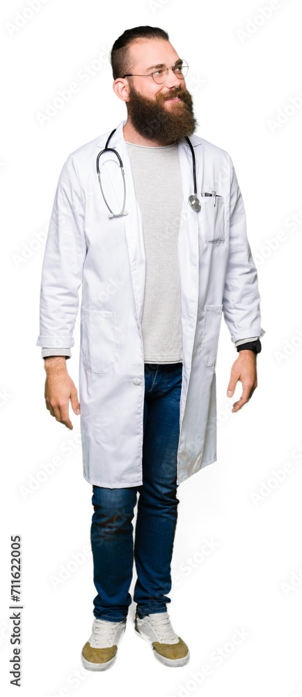 Young blond doctor man with beard wearing medical coat looking away to side with smile on face, natural expression. Laughing confident. Young blond doctor man with beard wearing medical coat looking away to side with smile on face, natural expression. Laughing confident.