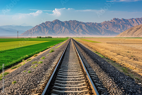 Railway extending towards mountains under blue sky