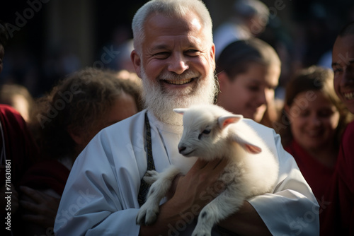 Saint Anthony's blessing of animals. Priest holds small lamb in his arms after it was blessed during celebration of Saint Anthony photo