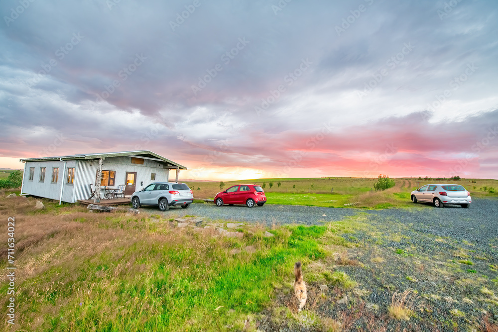 Isolated home with parked cars at sunset, Iceland