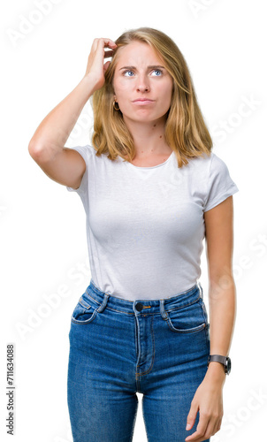 Beautiful young woman wearing casual white t-shirt over isolated background confuse and wonder about question. Uncertain with doubt, thinking with hand on head. Pensive concept.