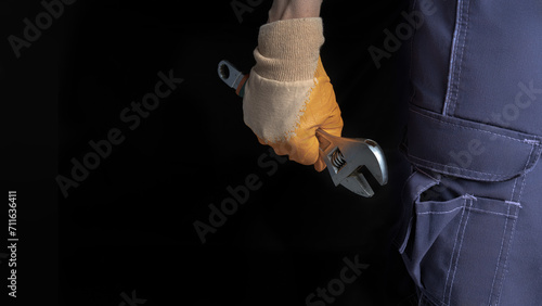 A man's hand holds an adjustable wrench on a black background. Place to place text. photo