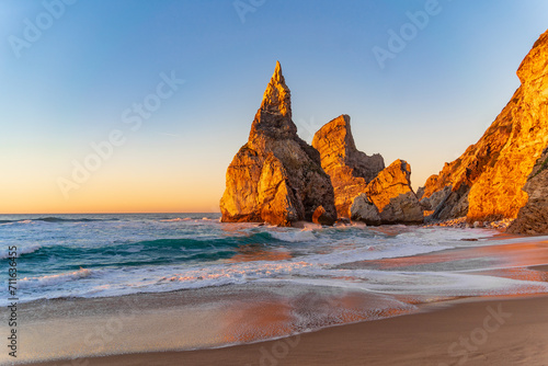 Sunset on the Portugal Ursa Beach, Praia da Ursa, 
the westernmost beach at atlantic coast of Atlantic Ocean with sand and sunset sun waves and foam at sand of coastline picturesque landscape panorama