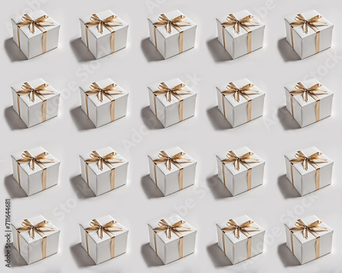 Seamless pattern of white gift boxes with gold ribbons on a white background photo